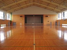 an indoor basketball court with hard wood flooring and large windows on the side wall