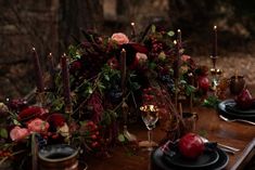 a wooden table topped with black plates and red flowers