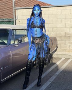 a woman dressed in blue and black standing next to a car with long braids