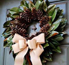 a wreath on the front door decorated with pine cones and ribbon tied in a bow