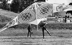 two people are flying a large kite in the grass