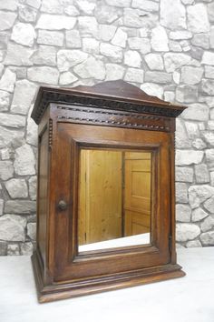 an old wooden mirror sitting on top of a white counter next to a stone wall