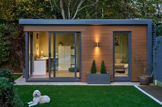 a dog laying on the grass in front of a small house with sliding glass doors