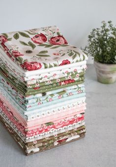 a stack of cloths sitting on top of a table next to a potted plant