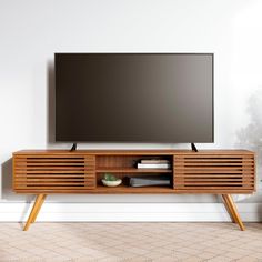 a flat screen tv sitting on top of a wooden entertainment center next to a potted plant