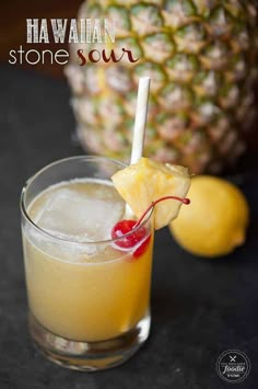 a pineapple drink with a cherry garnish on the rim, in front of a pineapple