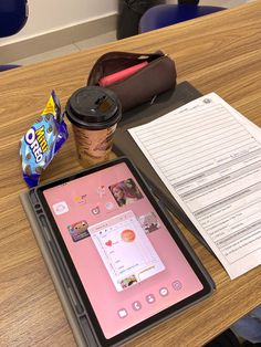 a tablet computer sitting on top of a wooden table next to a cup of coffee