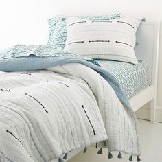 a bed with blue and white pillows on top of it next to a night stand