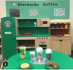 a green table topped with donuts and drinks next to a starbucks coffee kiosk