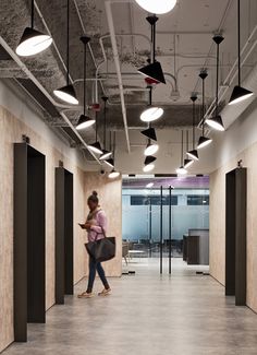 a woman walking down a hallway with lots of lights