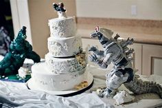 a wedding cake decorated with godzilla figurines on a table in a kitchen area