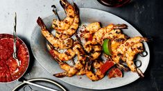 grilled shrimp and peppers on a plate next to a glass of red wine with scissors