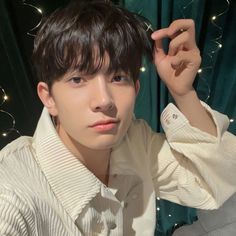 a young man is posing for a photo in front of a curtain with lights behind him