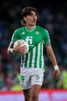 a man holding a soccer ball in his hands on a field with people watching from the stands