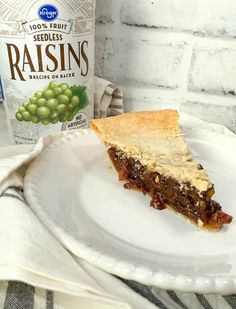 a piece of pie on a white plate next to a bottle of raisins