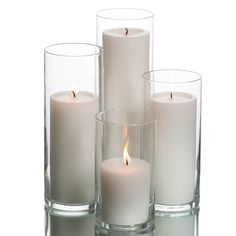 three white candles are sitting in glass vases