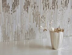 a vase filled with flowers sitting on top of a white table next to a curtain