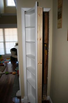 a tall white book shelf sitting in the corner of a room next to a doorway