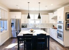 a kitchen with white cabinets and black chairs