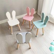 four children's chairs in various colors and shapes, sitting on the floor next to a window