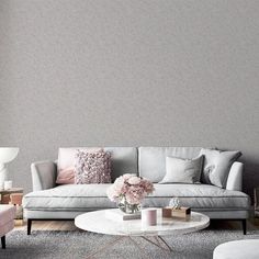 a living room filled with furniture and flowers on top of a coffee table in front of a gray wall