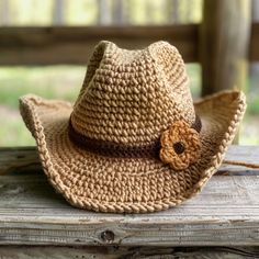 a straw hat with a flower on it sitting on a wooden bench in the sun