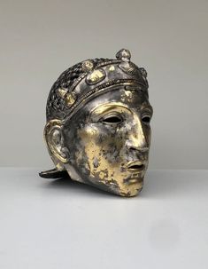 a gold and silver mask on a white table with grey background, close up view