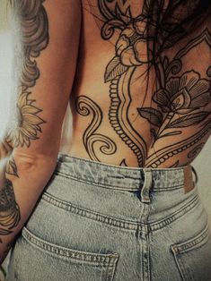 the back of a woman's body with tattoos on it