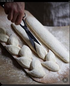 a person cutting bread with a pair of scissors on top of it next to some uncooked dough