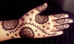 a woman's hand with henna tattoos on it and flowers all over the palm