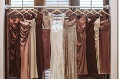 the bride's dresses are hanging up in front of the window and on the clothes rack