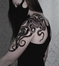 a woman wearing a black top with an octopus tattoo on her arm and shoulder,