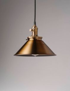 an industrial style pendant light hanging from the ceiling in a gray room with white walls