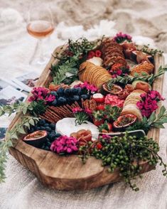 a wooden platter filled with different types of food on top of a white table cloth