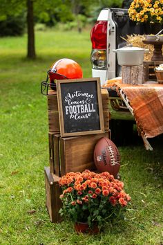 a football themed table with flowers and an old fashioned wooden crate on the grass next to it