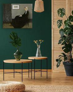 a living room with green walls and plants on the tables in front of it,