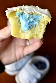 a person holding up a piece of cake with blue icing on it in their hand