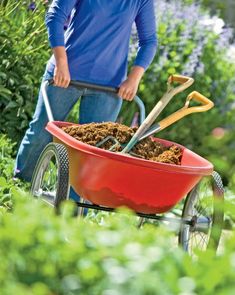 a man pushing a wheelbarrow filled with dirt and gardening utensils in the garden