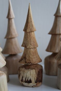 several wooden christmas trees lined up on a white table top with one standing out from the others