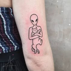 a person with a tattoo on their arm holding a baby in his arms and the outline of an alien