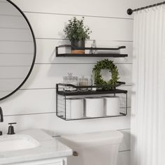 the bathroom is decorated in white and has black shelves with plants on top of them