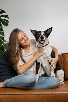 a woman sitting on top of a couch holding a black and white dog in her arms