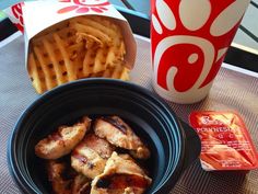 a bowl of chicken and waffles next to a cup of coffee on a table