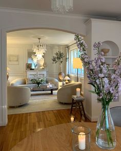 a living room filled with furniture and flowers in a vase on top of a wooden table