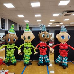 three inflatable figures are standing on the floor with balloons attached to their heads