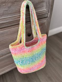 a multicolored crocheted bag hanging on a dresser