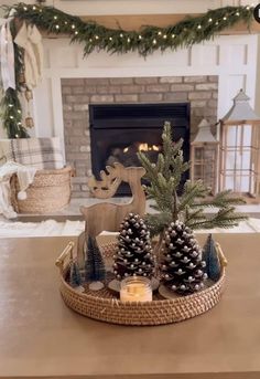 a tray with pine cones and candles on top of a table in front of a fireplace