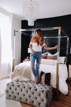 a woman standing on top of a bed in a bedroom