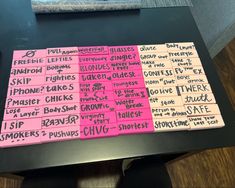 pink and black sticky notes sitting on top of a table