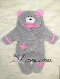 a gray teddy bear with pink ears on it's head and feet is laying down